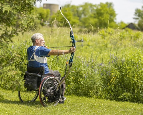 A man in a wheelchair shoots an arrow.
