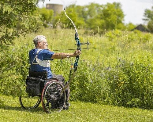 A man in a wheelchair shoots an arrow. A man in a wheelchair shoots an arrow.