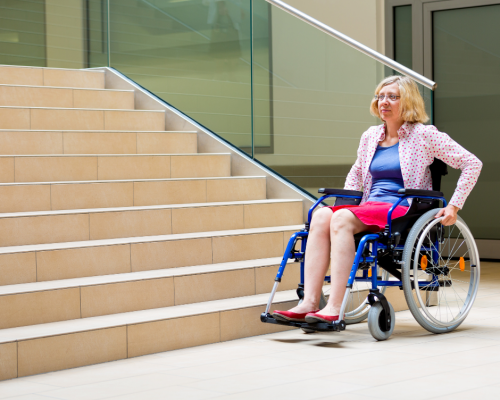 Woman using wheelchair stuck at the bottom of stairs with no accessible route available.