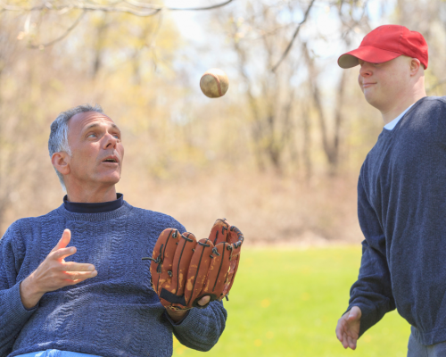 A man with a spinal cord injury plays ball with his son.