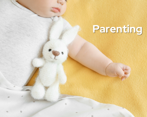 Baby sleeping with stuffed bunny cuddled beside.