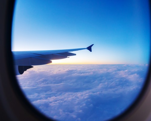 A view of. the sky, a sunset and a plane wing looking out from the plane window.