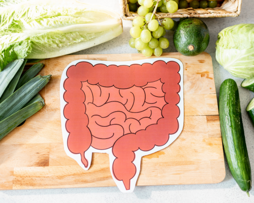 paper cut out of a bowel on a cutting board with fruit and vegetables around it