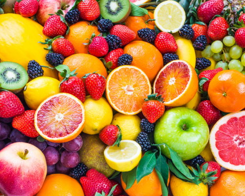 A huge mound of fruit including grapefruit, berries, grapes and tangerines