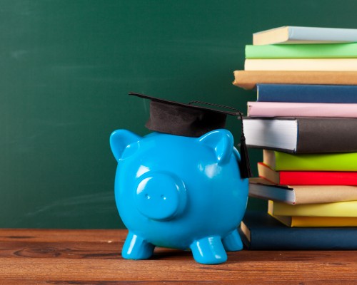 piggy bank with scholar cap and stack of books beside