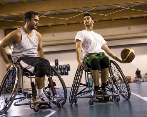 Two guys in sport wheelchairs playing basketball