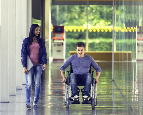 male student rolling down the hall walking with a female friend