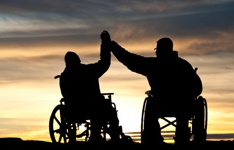 Two guys with spinal cord injuries giving each other a 'high five'